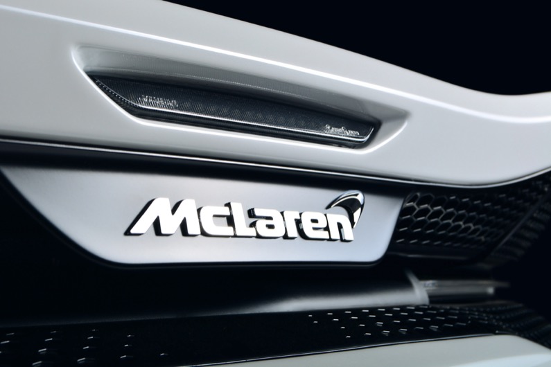 Mclaren GT rear emblem shot on a white car against a dark background, shot under studio lighting.